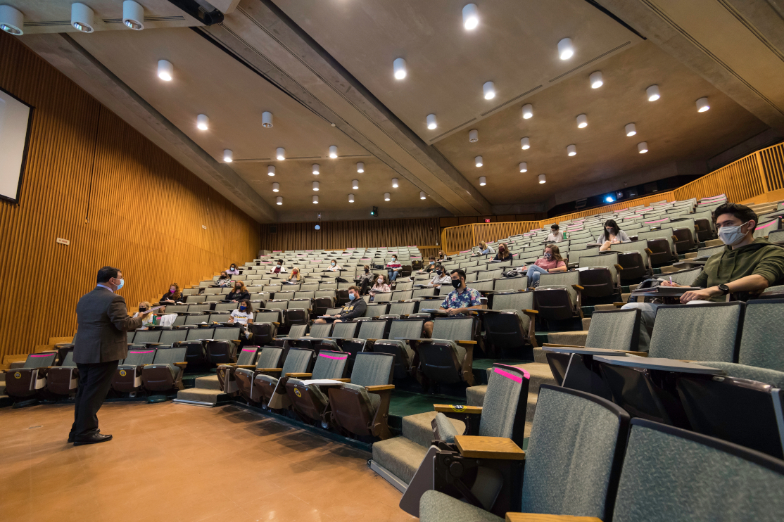 A speaker addresses an audience in a large classroom