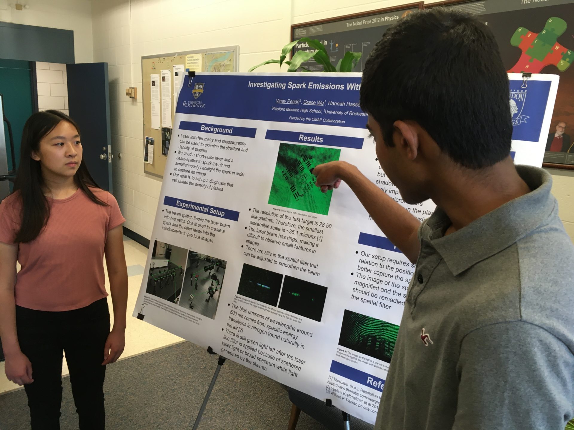 Two high school students show their physics work at a poster session