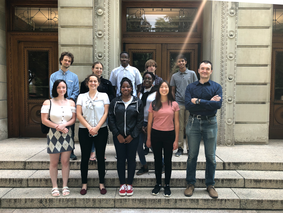 Smiling students and professor standing on stone steps